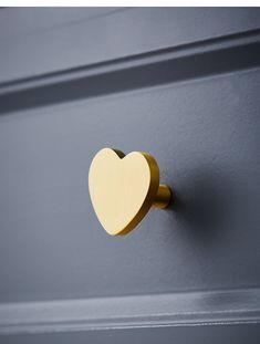 a heart shaped wooden door handle on a gray painted wall