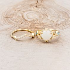 a gold ring with an opal center surrounded by blue and white stones on a piece of wood