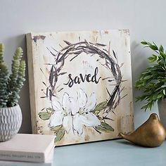 a wooden sign sitting on top of a table next to a potted plant and books