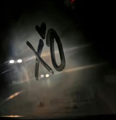 the word xo spelled out in front of a dark background with lights and fog