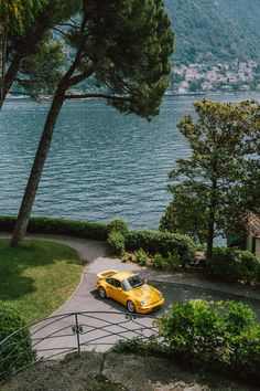 a yellow car parked on the side of a road next to a body of water