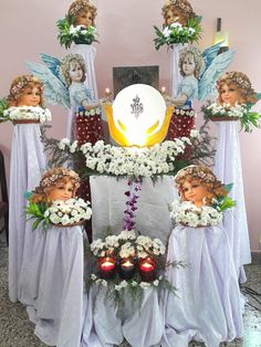 an arrangement of flowers, candles and angel heads are on display in front of the altar