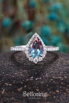 a pear shaped blue and white diamond ring on top of a rock