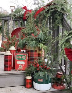 christmas decorations are sitting on the steps in front of a porch with red and green tin canisters