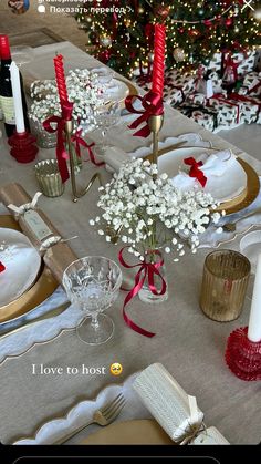 the table is set for christmas dinner with red and white decorations, candles, and flowers