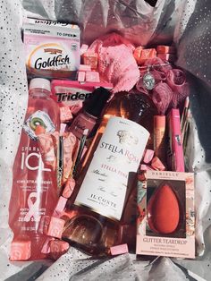 a bag filled with lots of different types of cosmetics and hygiene products on top of a white sheet