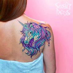 the back of a woman's shoulder with a colorful unicorn tattoo design on it