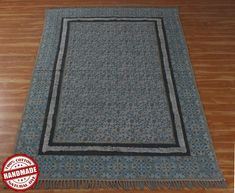 a blue rug on the floor with a wooden floor in front of it and a red sticker that says handmade