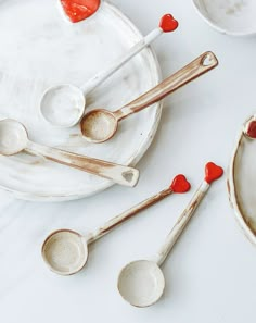 spoons and bowls with hearts on them sitting on a white counter top next to each other