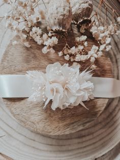 a white flower on top of a wooden table next to a ribbon and some flowers