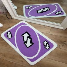 two purple and white rugs sitting on top of a wooden floor next to a mirror