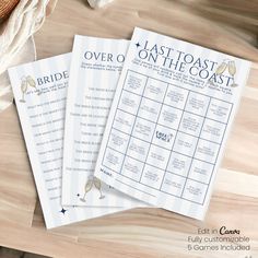 three wedding game cards sitting on top of a wooden table next to a white towel