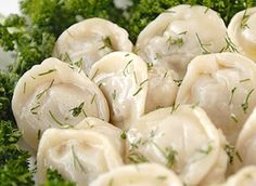 some dumplings and broccoli on a white plate with green garnish