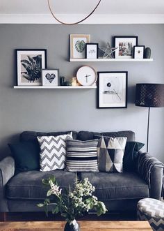 a living room with grey walls and pictures on the wall above the gray couches