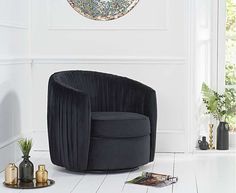 a black chair sitting on top of a white floor next to a vase and potted plant