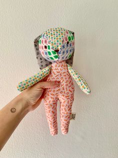 a hand holding an origami doll in the shape of a person's head