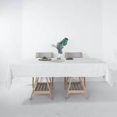 a white table with two chairs and a potted plant