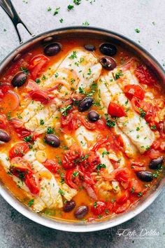 fish with tomatoes, olives and capers in a pan on a table top