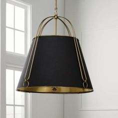 a black and gold lamp hanging from a ceiling fixture in a room with white walls