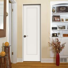 a white door in a living room next to a vase with flowers