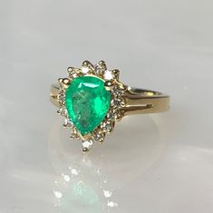 an emerald and diamond ring is shown on a white surface, with the center stone surrounded by smaller diamonds