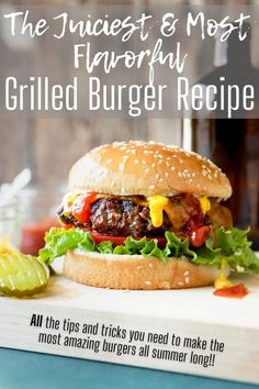 a burger with lettuce and tomato on it sitting on top of a wooden cutting board