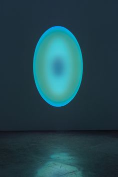 a blue circular object in the middle of a dark room with water on the floor