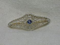 "On offer today is a gorgeous little filigree brooch, coming to us in time from the Art Deco 1920s. The stone is a natural Ceylon Sapphire (tested and guaranteed). It's a lovely cornflower blue color, very popular in this time. The round faceted stone spans 3.02mm for an approximate weight of .10 carat. MARKINGS: 14K Front is white gold Back is green gold Pin bar is yellow gold MEASUREMENTS: About 1 3/8\" long by 1/2\" wide. WEIGHT: 3.4g total CONDITION: Excellent vintage condition! This will be Heirloom Style Oval Filigree Brooch, Heirloom Filigree Oval Brooch, Heirloom Oval Filigree Brooch, Oval Art Deco Brooch For Formal Occasions, Art Deco Oval Brooch For Anniversary, Antique Filigree Brooch For Formal Occasions, Oval Art Deco Brooches For Formal Occasions, Art Deco Formal Oval Brooches, Antique Filigree Brooches For Formal Occasions