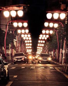 some cars are driving down the street at night