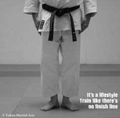 black and white photograph of a man in karate attire standing with his hands on his hips