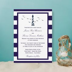 a blue and white striped wedding card with a lighthouse in the background on a table