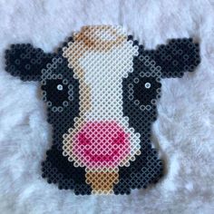 a black and white cow with pink nose is shown on a white background, made out of perler beads