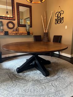 a round wooden table sitting on top of a rug in front of a wall mounted mirror