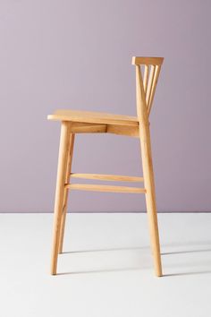 a wooden chair sitting on top of a white floor next to a purple wall in front of it