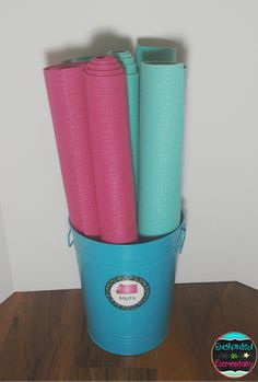 four yoga mats in a bucket on a table