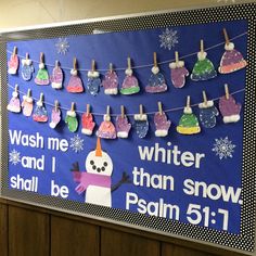 a bulletin board with snowmen and clothes hanging from the line on it's sides