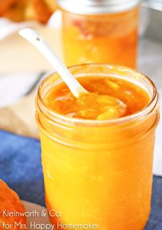 two jars filled with orange liquid on top of a blue cloth next to pumpkins