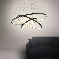 a modern chandelier hanging from the ceiling over a black couch in an empty room