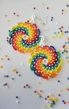 multicolored beaded earrings on white background with beads scattered all around the image