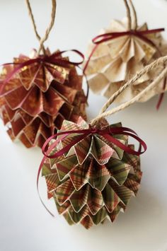 two paper christmas ornaments hanging from twine