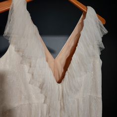 a white dress hanging on a wooden hanger