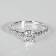 a white gold engagement ring with a princess cut diamond and pave set diamonds on the band