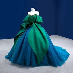 Unveil a world of elegance and sophistication with this stunning green and blue evening gown. Meticulously crafted from luxurious fabrics, this dress features a striking off-shoulder design that highlights the neckline with delicate beadwork. The voluminous silhouette is adorned with layers of intricate tulle, creating an ethereal flow that is perfect for making a grand entrance at any formal event.The bodice is designed with a flattering sweetheart neckline and adorned with shimmering embellishments for a touch of glamour. The exquisite green overlay wraps around the waist, cascading down to form a beautiful contrast with the blue tulle skirt beneath. The intricate pleating and dramatic bow accentuate the waist, creating an hourglass silhouette that enhances every body type.Perfect for ga Peacock Ball Gown, Elegant Green Off-shoulder Ball Gown, Elegant Off-shoulder Green Ball Gown, Green Off-shoulder Gown For Wedding, Green Off-shoulder Ball Gown For Prom, Green Off-shoulder Gown For Prom Season, Off-shoulder Green Gown For Prom Season, Green Off-shoulder Gown For Prom, Green Organza Evening Dress For Prom