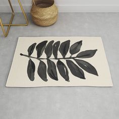 a black and white leaf rug on the floor next to a basket with a plant in it