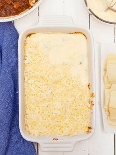 a casserole dish with cheese on top and other food items around the bowl