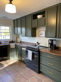 a kitchen with green cabinets and an oven in the middle of the countertop area