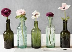 four bottles with flowers in them sitting on a table