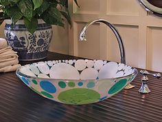 a bowl shaped sink sitting on top of a counter next to a potted plant