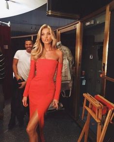 a woman in a red dress is posing for a photo while another man looks on