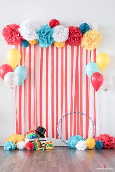 balloons and streamers are on the floor in front of a backdrop with red, white, and blue striped paper flowers